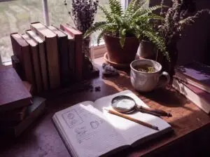 Books, notebook & magnifying glass arranged for careful spiritual research.
